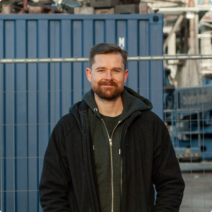Smiling man standing confidently at an industrial site, representing the company's team and reliability.